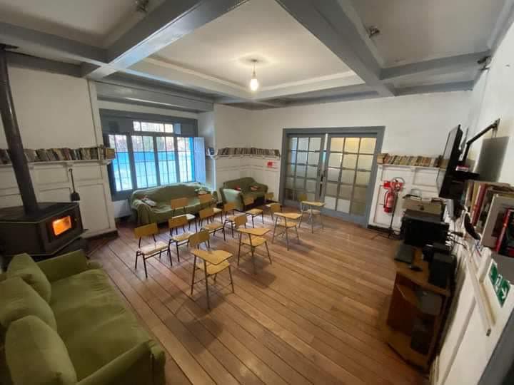 Sala de estar con estufa a leña, sillas y estantes con libros